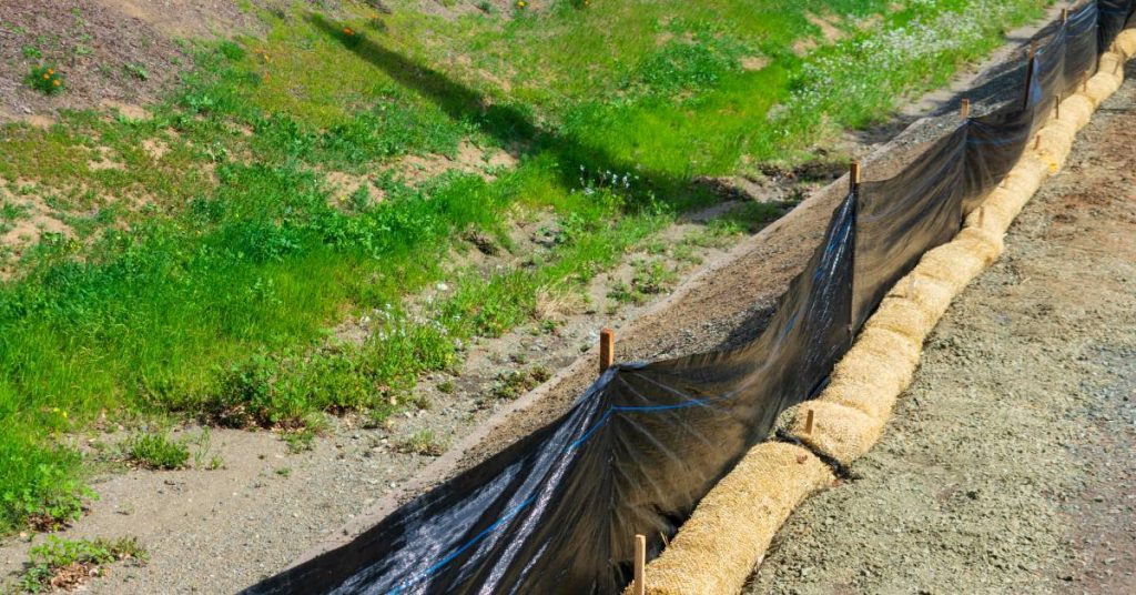 An attempt at erosion control utilizing plastic fences and straw wattles to retain sediment at a construction site.