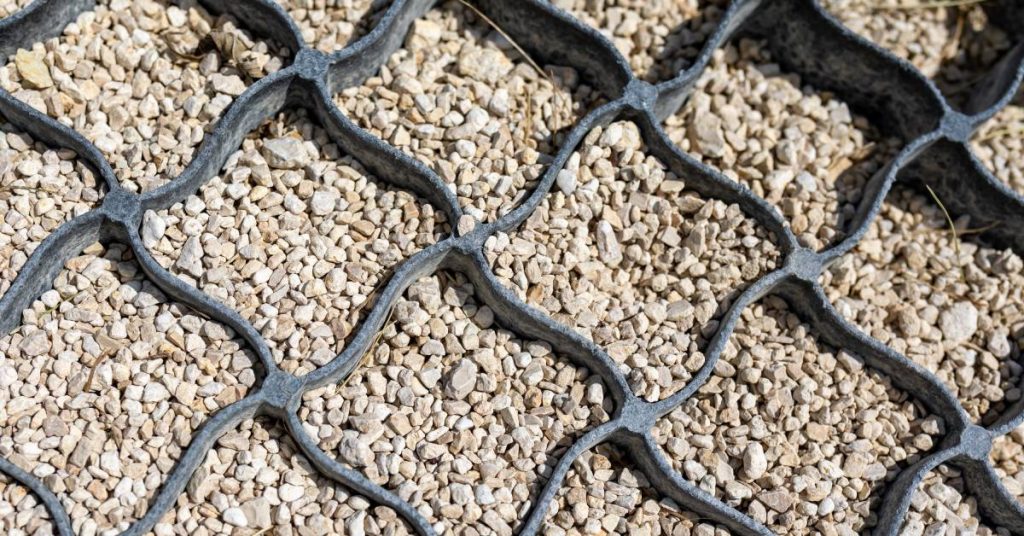 A cellular retention system for sediment control. The warped black plastic grid is full of white gravel.